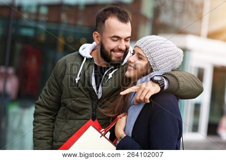 Portrait of happy couple with shopping bags after shopping in city