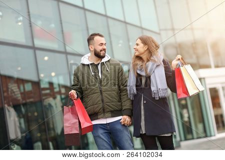 Portrait of happy couple with shopping bags after shopping in city