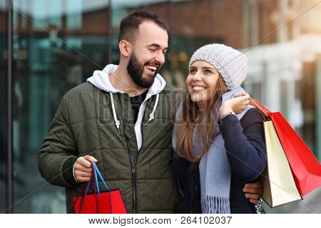 Portrait of happy couple with shopping bags after shopping in city