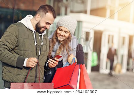 Portrait of happy couple with shopping bags after shopping in city