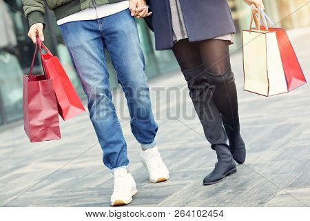 Legs of couple with shopping bags after shopping in city