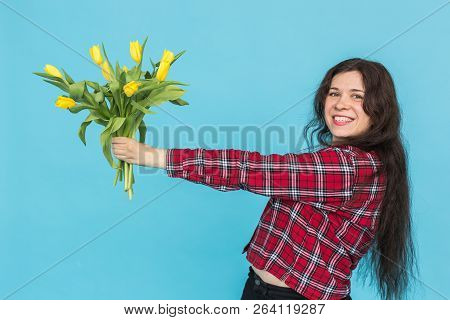 Laughing Young Caucasian Woman With Bouquet Of Tulips On Blue Background.