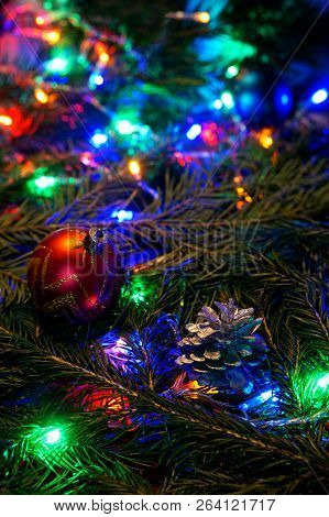 A Red Golden Ball And A Cone Lie On The Branch Of A Tree Among The Multicolored Lights. Congratulati