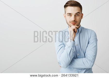 Smart Ambitious Handsome Male In Trendy Blue Collar Shirt Holding Hand On Chin Smirking From Interes