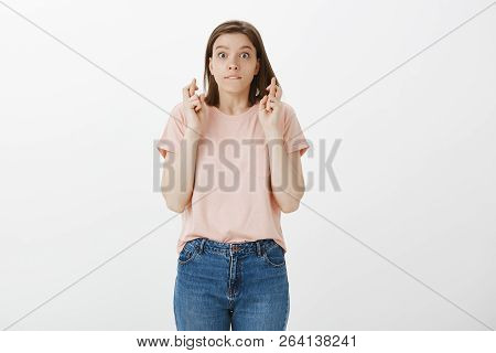 Studio Shot Of Attractive Emotive Young European Girl In Pink T-shirt, Biting Lip And Staring With P
