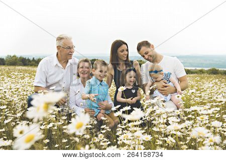 Family With Grandparent Spending Time With Little Child During The Sunset.