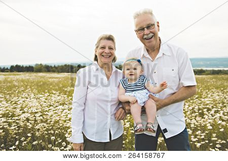 Grandparent Spending Time With Little Child During The Sunset.