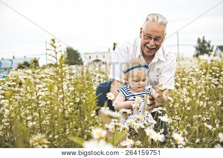 Grandfather Spending Time With Little Child During The Sunset.