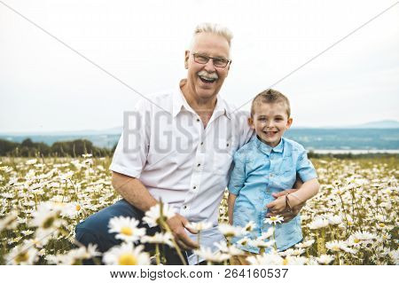 Grandfather Spending Time With Little Child During The Sunset.