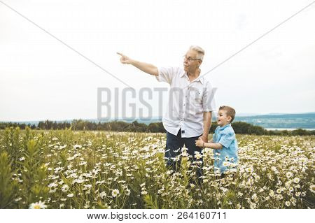 Grandfather Spending Time With Little Child During The Sunset.
