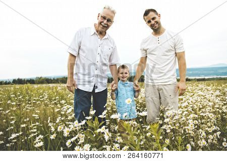 Grandfather And Son Spending Time With Little Child During The Sunset.