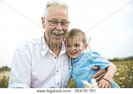 Grandfather Spending Time With Little Child During The Sunset.