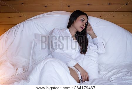 The Beautifu Laday Is Layingdown On Bed,put Her Hand Touch Head,unhappy Feeling,serious Emotion,trie