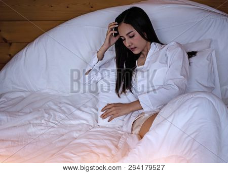 The Beautifu Laday Is Sitting On Bed,put Her Hand Touch Head,unhappy Feeling,headache From Tried And