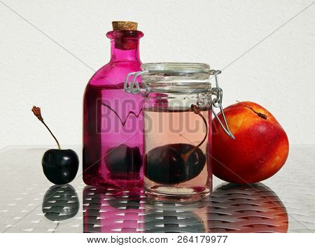 Still Life With Fresh Compote In Vintage Glass Botlles, Nectarine And Ripe Cherries Against A High K