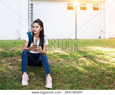 The Beauty Lady Is Sitting On Green Grass Ground Floor,turn Face To The Right Side For Looking Somet