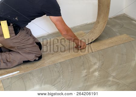 Work On Laying Flooring. Worker Installing New Vinyl Tile Floor.