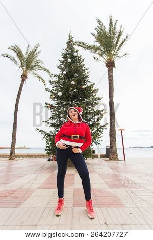 Christmas, Holidays And Humor Concept - Young Happy Woman Have Fun In Christmas Costume At Summer Ne