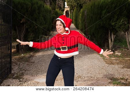 Christmas, Holidays, Humor And People Concept - Funny Happy Woman In Santa Suit Dancing Outdoors