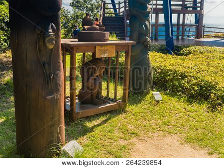 Samcheok, South Korea; September 25, 2018: Young Girl In Wooden Cage Chained To Phallic Shaped Statu