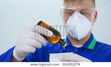 A Young Professional Master Holds A Jar In A White Coat, Safety Goggles, White Rubber Gloves.