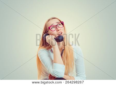 Young Blond Woman In Eyeglasses Looking Up In Boredom And Irritation While Speaking On Telephone