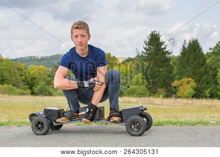 Young Caucasian Man Drives Electrical Mountainboard On Road In Nature