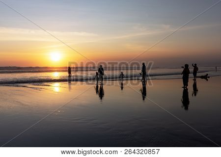 Silhouettes Of People Enjoying Sunset In Seminyak Beach, Kuta, Bali, Indonesia.
