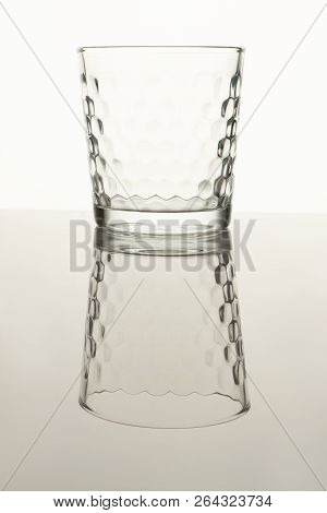 Empty Full Shot Glass. Small Glass On A Reflective Surface On White Isolated Background.