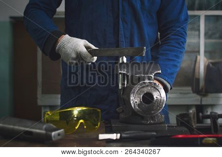 Man Worker Is Working With Iron Detail On Vise Grip On Blacksmith Table And Using A File.