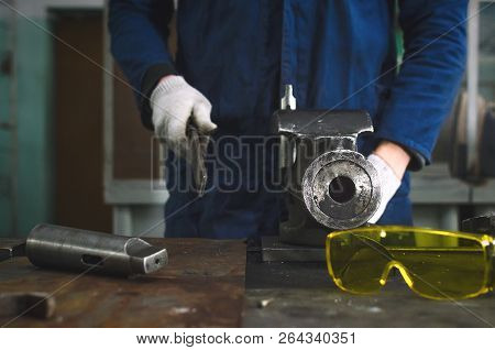 Man Worker Is Working With Iron Detail On Vise Grip On Blacksmith Table And Using A File.