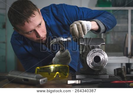 Man Worker Is Working With Iron Detail By Hammer On Vise Grip On Blacksmith Table.