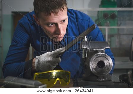 Man Worker Is Working With Iron Detail On Vise Grip On Blacksmith Table And Using A File.