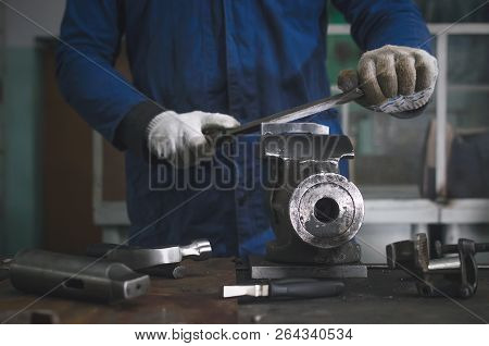 Man Worker Is Working With Iron Detail On Vise Grip On Blacksmith Table And Using A File.