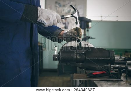 Man Worker Is Working With Iron Detail By Hammer On Vise Grip On Blacksmith Table.