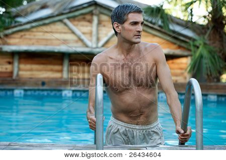 Handsome man coming out of the swimming pool and looking away