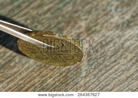 Tweezers Holding Retro Copper Iron Coin On The Table