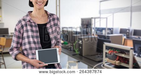 Smiling woman showing digital tablet against white background against empty chairs by desk with computers