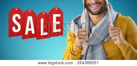 Portrait of smiling man holding wooly hat against abstract blue background