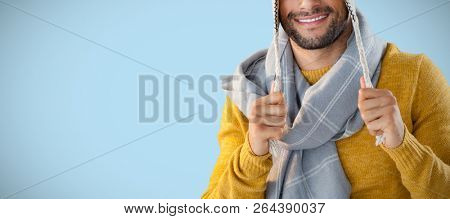 Portrait of smiling man holding wooly hat against blue background