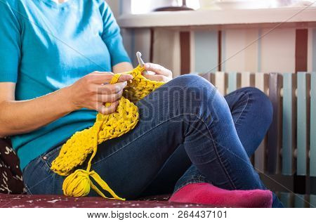 Woman Knits Crochet. The Girl Sits On The Couch And Knits From Knitting Yarn. Crochet Thick Threads.