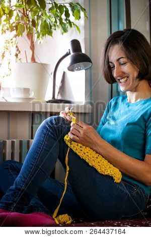 Woman Knits Crochet. The Girl Sits On The Couch And Knits From Knitting Yarn. Crochet Thick Threads.