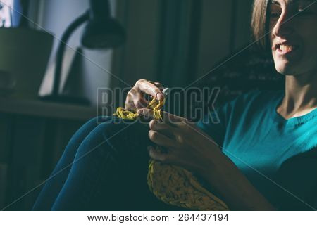 Girl Knits Crochet At Home. Woman Engaged In Needlework. A Knitter Sits On A Sofa And Works. Creativ
