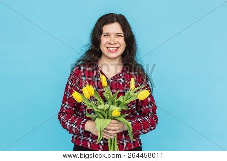 Laughing Young Caucasian Woman With Bouquet Of Tulips On Blue Background.