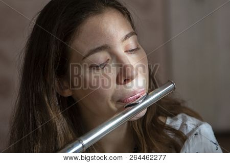 A Beautiful Woman Posing While Playing On A Flute