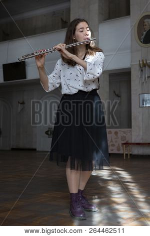 A Beautiful Woman Posing While Playing On A Flute