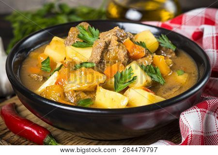 Goulash With Meat And Vegetables In Black Bowl. Beef Stew With Vegetables. European Cuisine.