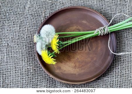 Bouquet Of Dandelions Tied With Twine On Round Clay Brown Dish. Rough Homespun Canvas, Burlap Of Jut