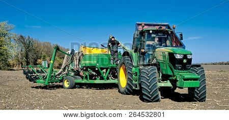 Russia, Krasnodar region, Kushevsky district.16.10.2018.   Modern, green tractor in the spring field work on the background of a beautiful rural landscape.