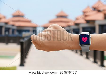 Woman Using Smart Watch Fitness App With Heart Rate Monitor On City Street